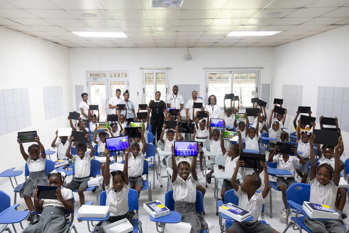 Pupils at a school run by the medical non-profit GHESKIO hold tablet computers they received for their studies, part of a broad range of services provided by the civic group with international support. (Haitian Global Health Alliance)